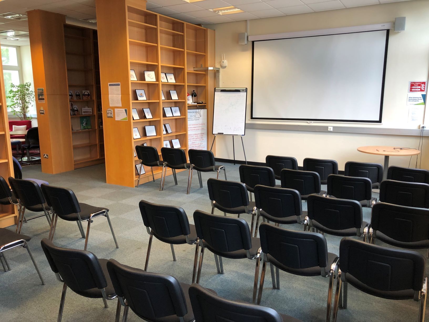 Newman Library lecture layout Photograph showing the lecture-style layout of the Newman Library - a room with five rows of chairs facing a projector screen on the end wall.